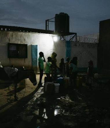 Children take turns filling jerrycans at a communal water point near a sprawling settlement camp in Adré, Chad.